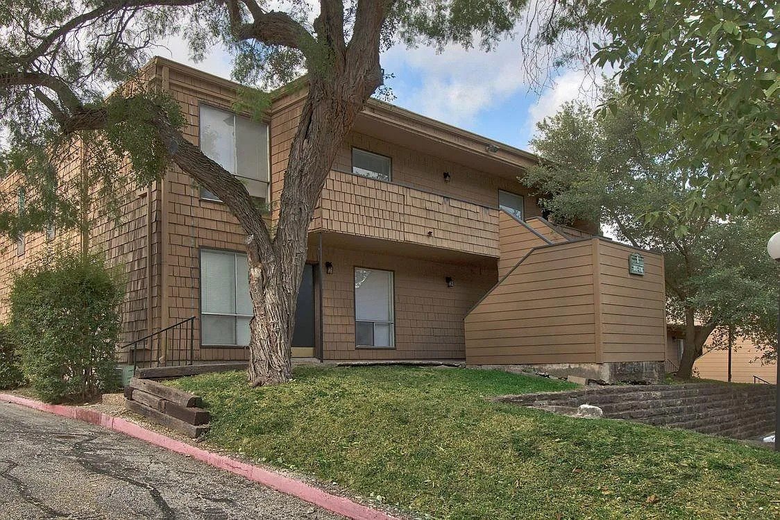 A brown house with a tree in front of it.